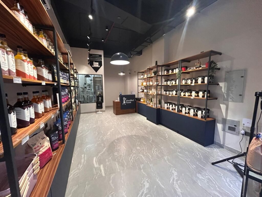Interior of the Slomilled store: shelves of oils, flours and spices either side of an aisle leading to the counter and milling room.